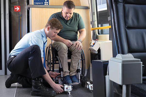 A Team member securing a customer's wheelchair using tie down straps.