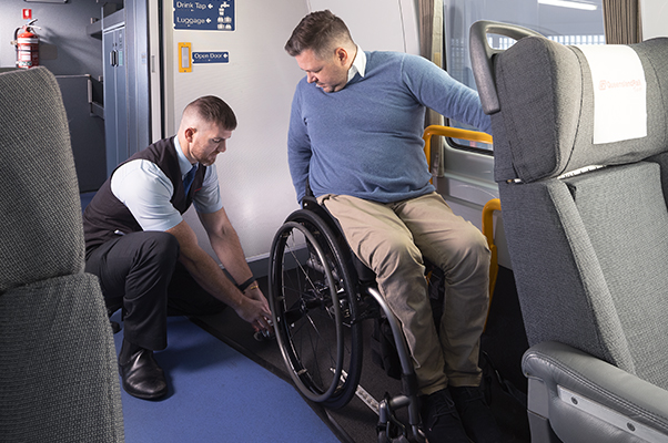 A Team member securing a customer's wheelchair using tie down straps.